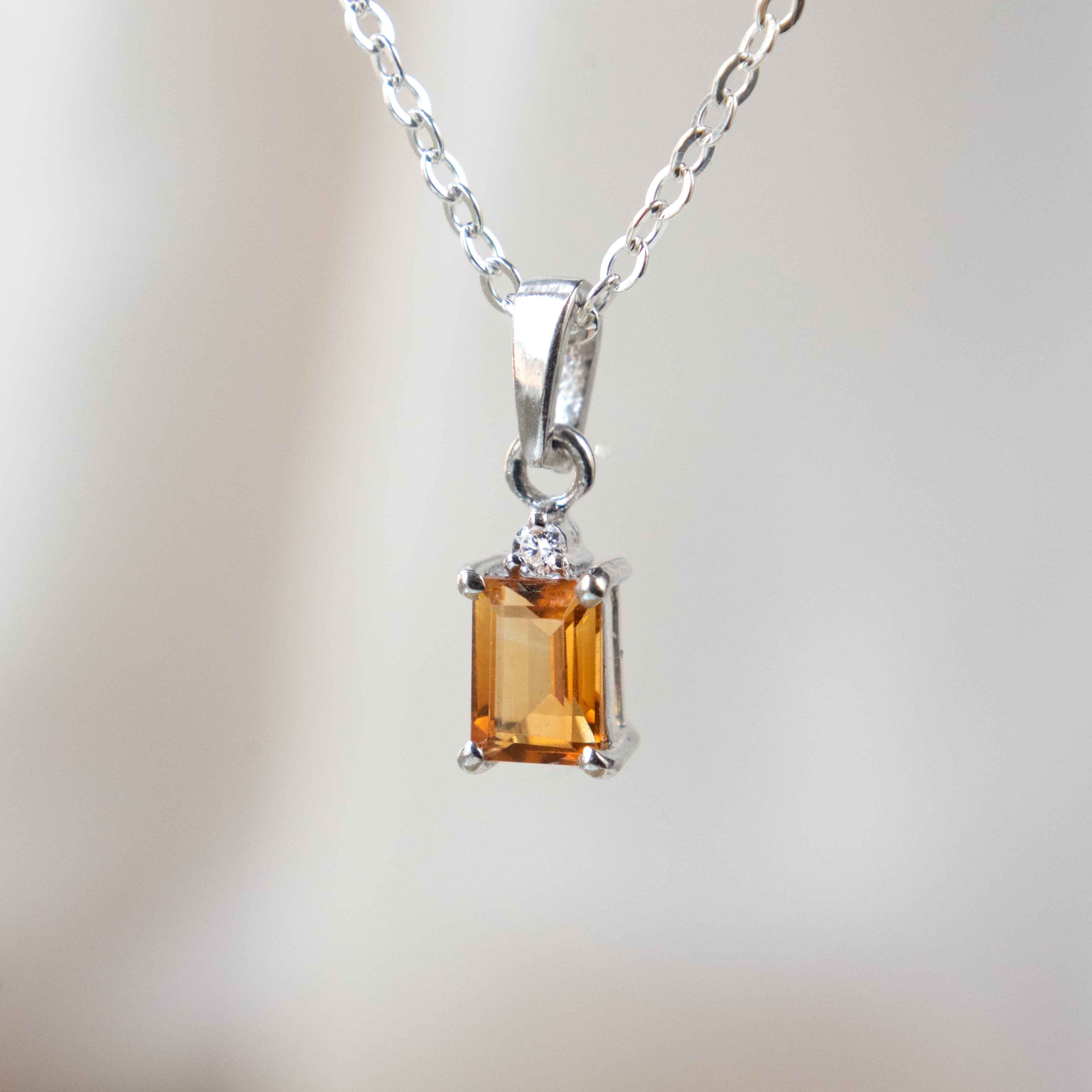 Silver necklace with a rectangular citrine pendant on a blurred background