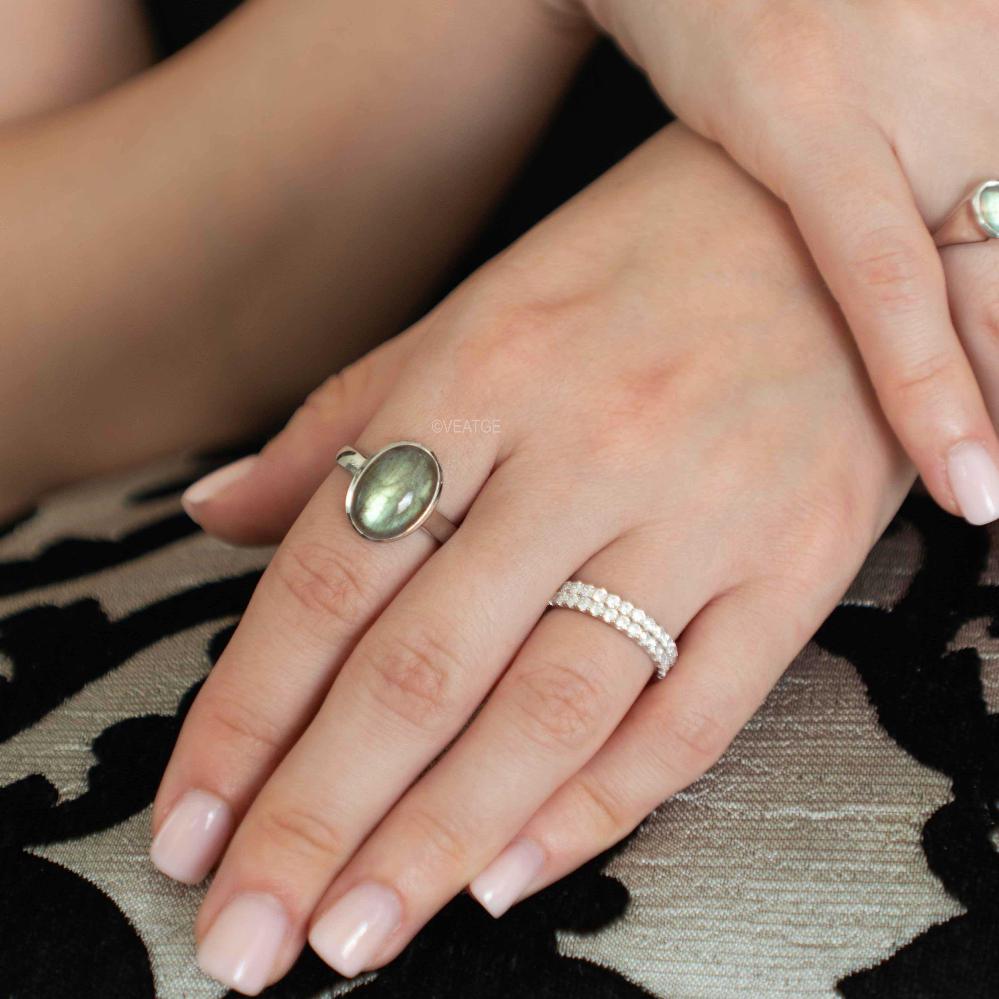 Close-up of hands wearing labradorite ring.