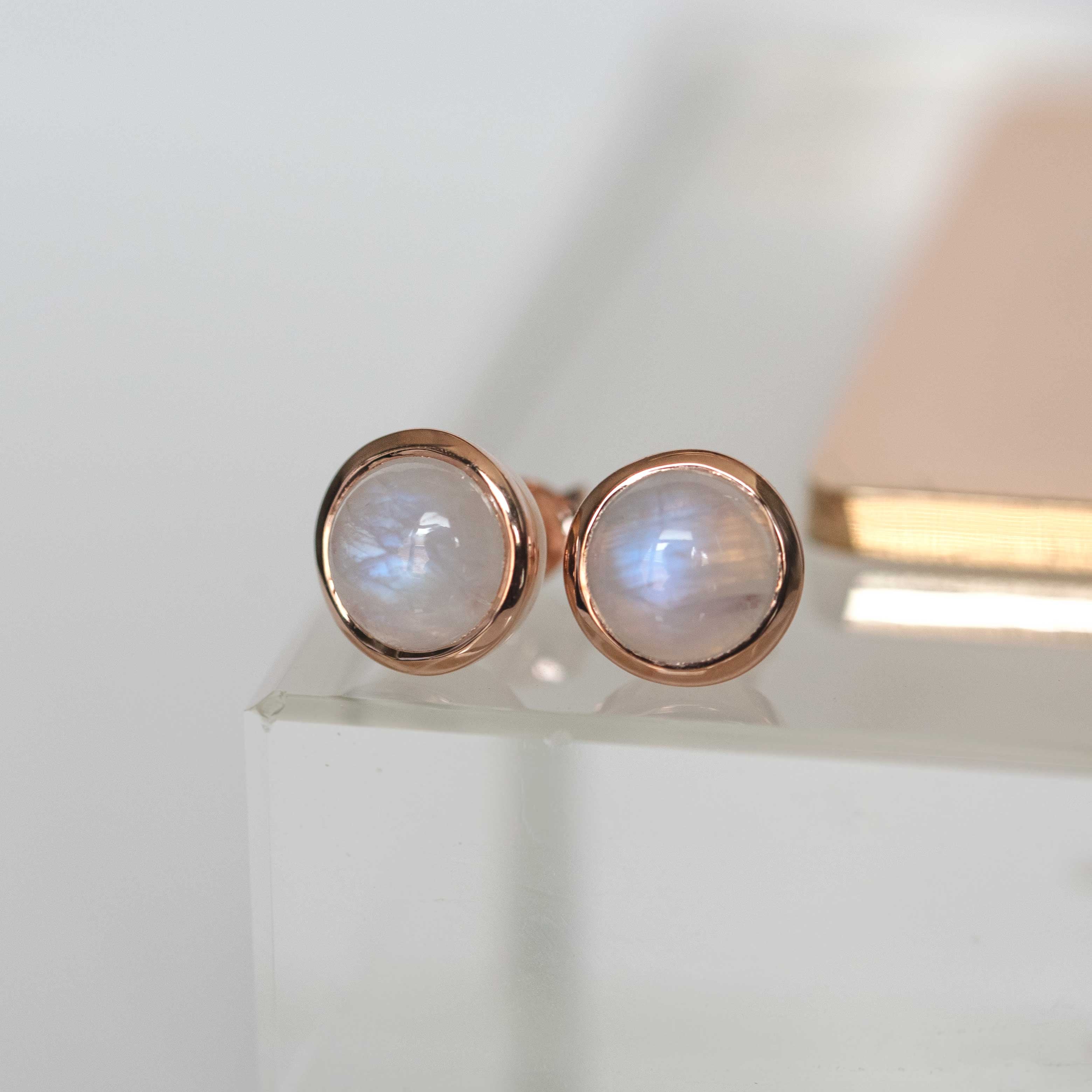 Rose gold earrings with moonstone stones on a white background