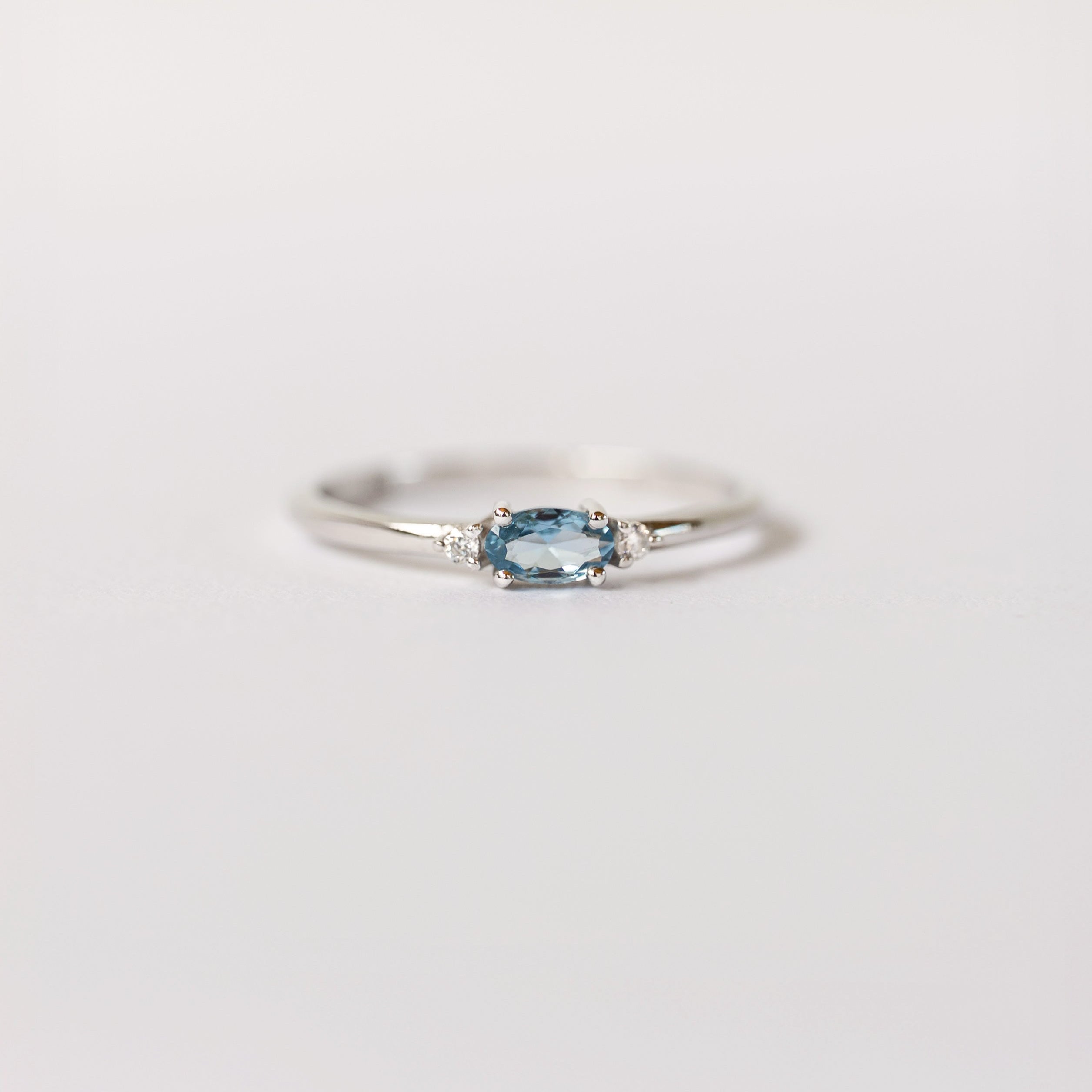 Silver dainty stacking ring with aquamarine gemstone on a white background, branded 'VEATGE'.