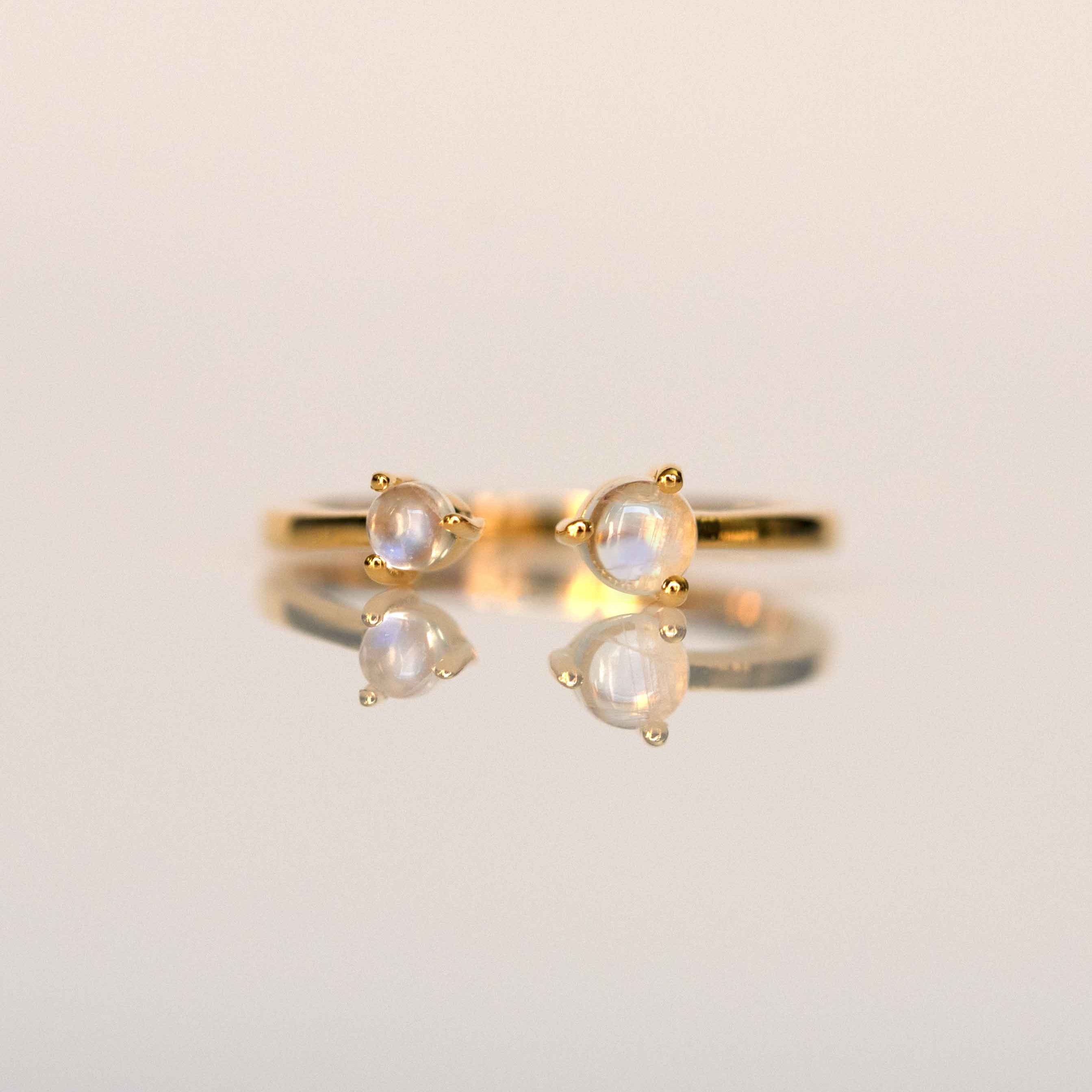An adjustable ring with a gold band and natural moonstone, displayed on a white background.