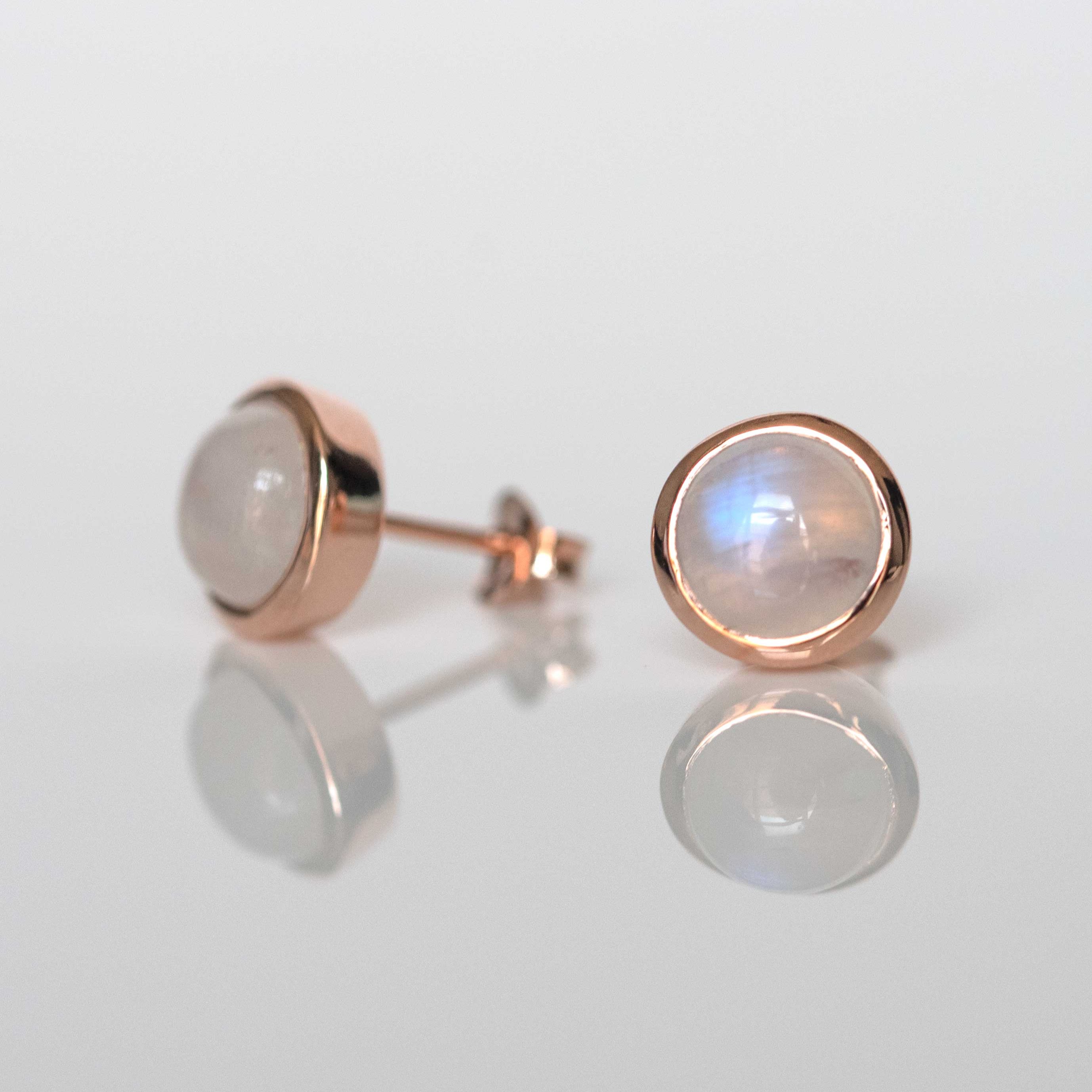 Pair of rose gold earrings with gemstones on a light gray background