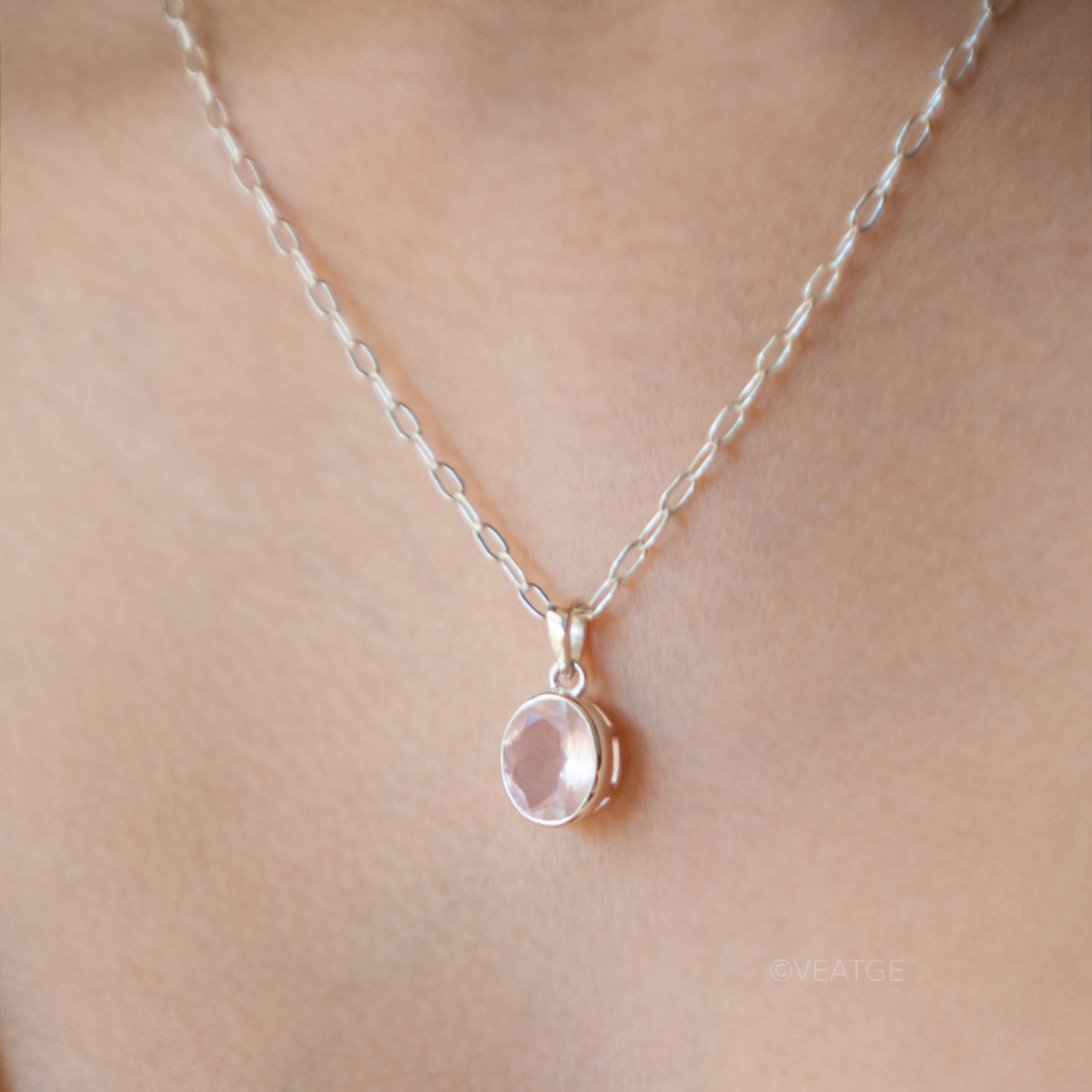 Silver necklace with a rose quartz pendant on a person's neck